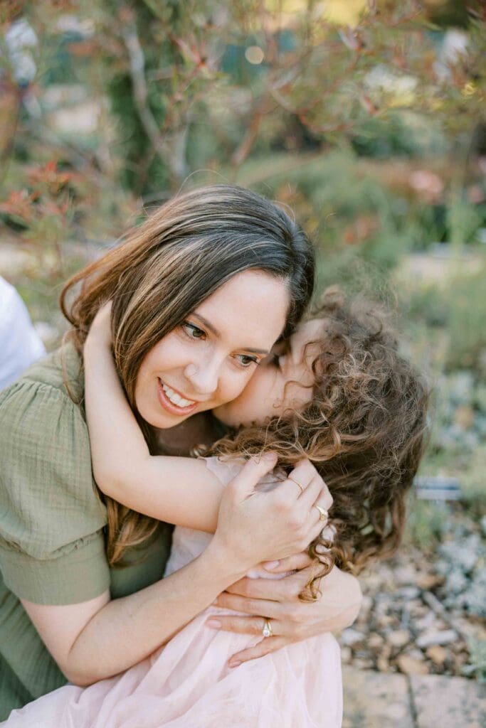 Young girl giving her mom a kiss on the cheek