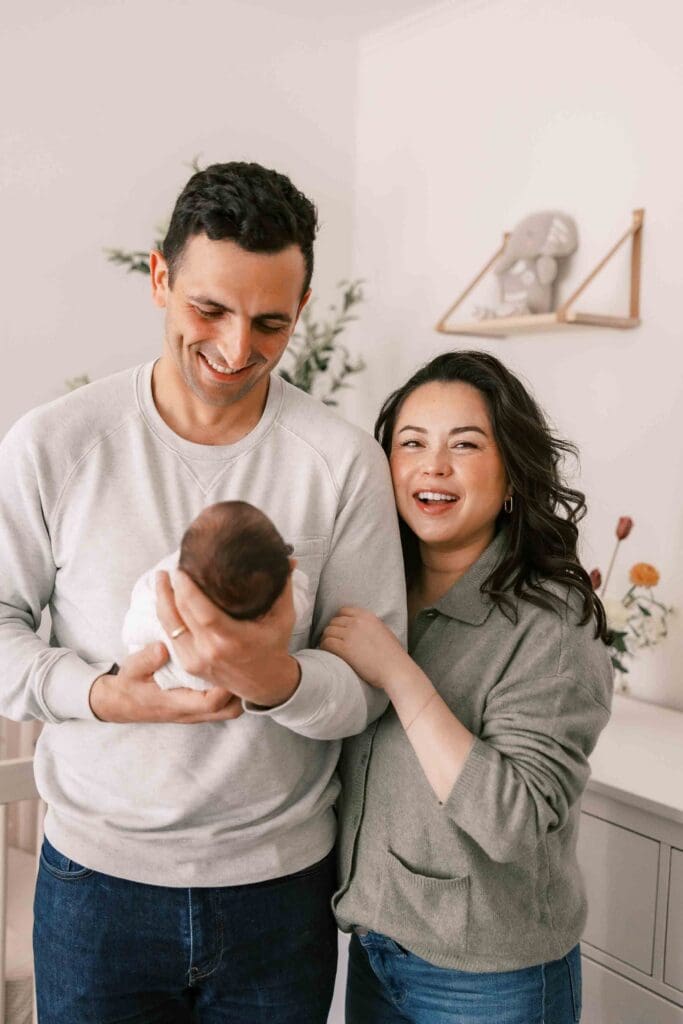 Parents smiling and holding their baby in their SF apartment