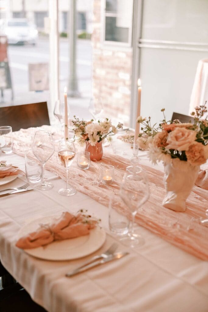 Beautiful pink table setting with tapered candles and floral arrangements