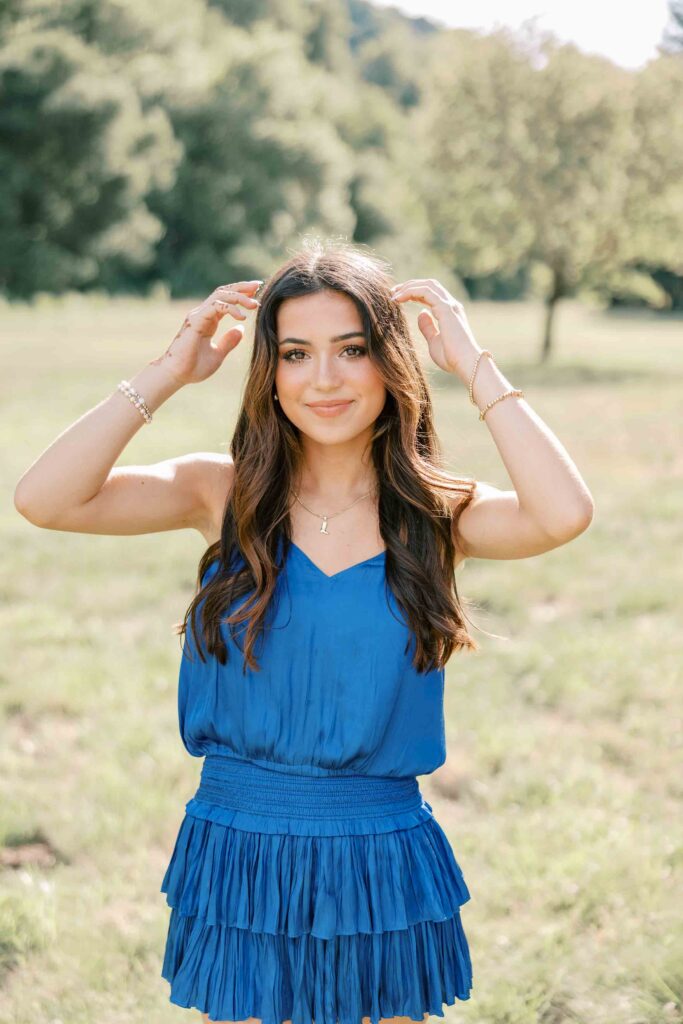 Brunette girl wearing a royal blue dress and playing with her hair