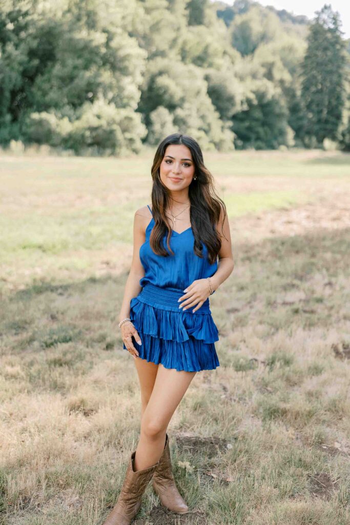 Brunette girl wearing a royal blue dress with her hands on her hips
