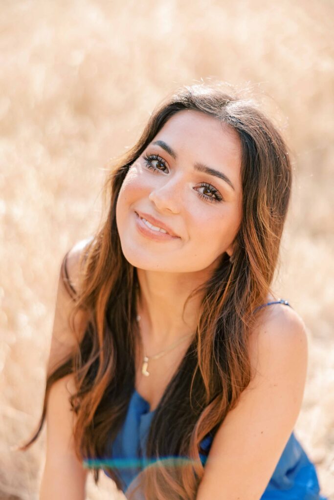 Brunette girl wearing a royal blue dress and looking up at the camera with a soft smile