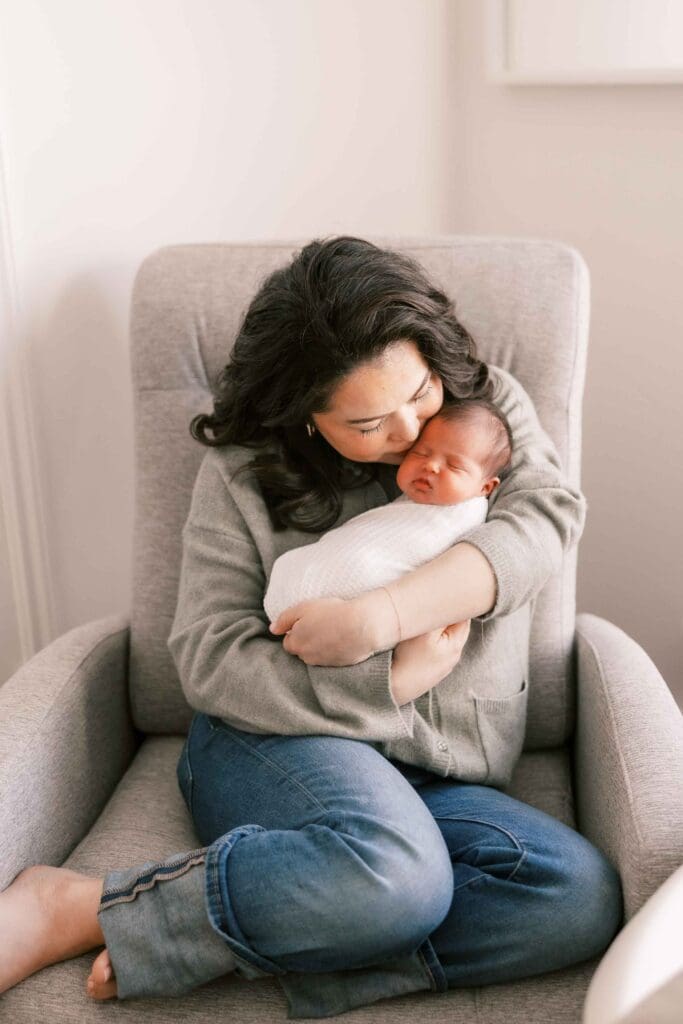 Mom snuggling her baby girl, wrapped in a white swaddle