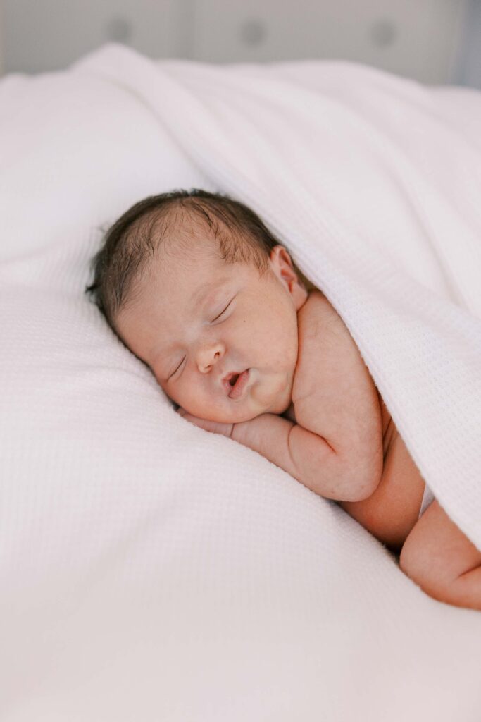 Newborn baby girl wrapped in white blankets in her apartment