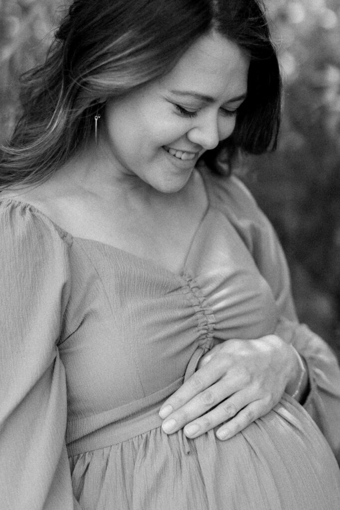 Maternity portrait of a mother to be holding her belly and smiling at it