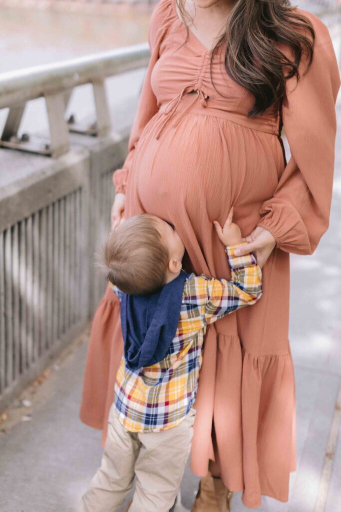 Maternity portrait of a toddler boy giving his mom's belly a kiss