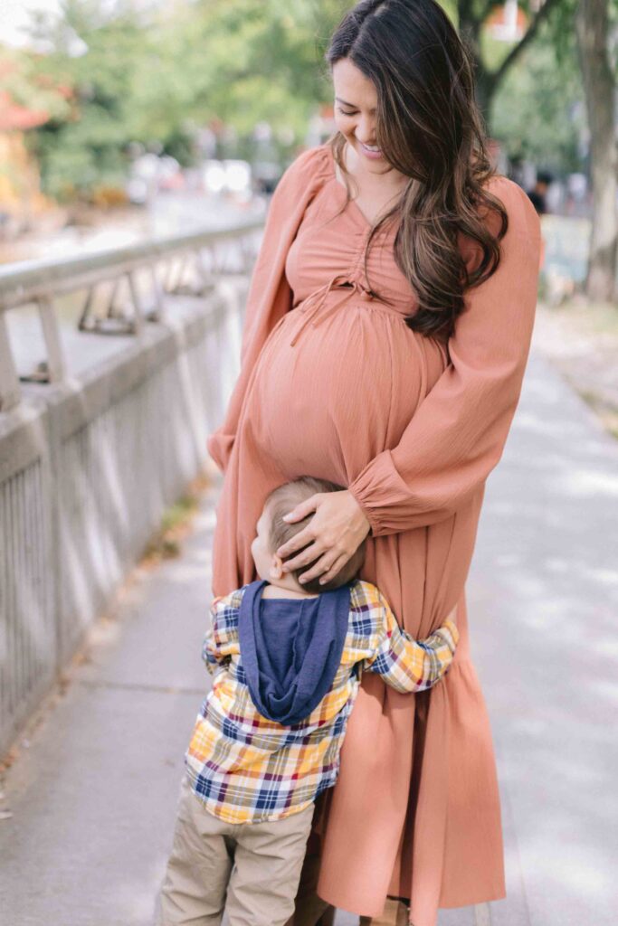 Maternity portrait of a toddler boy giving his mom's belly a hug