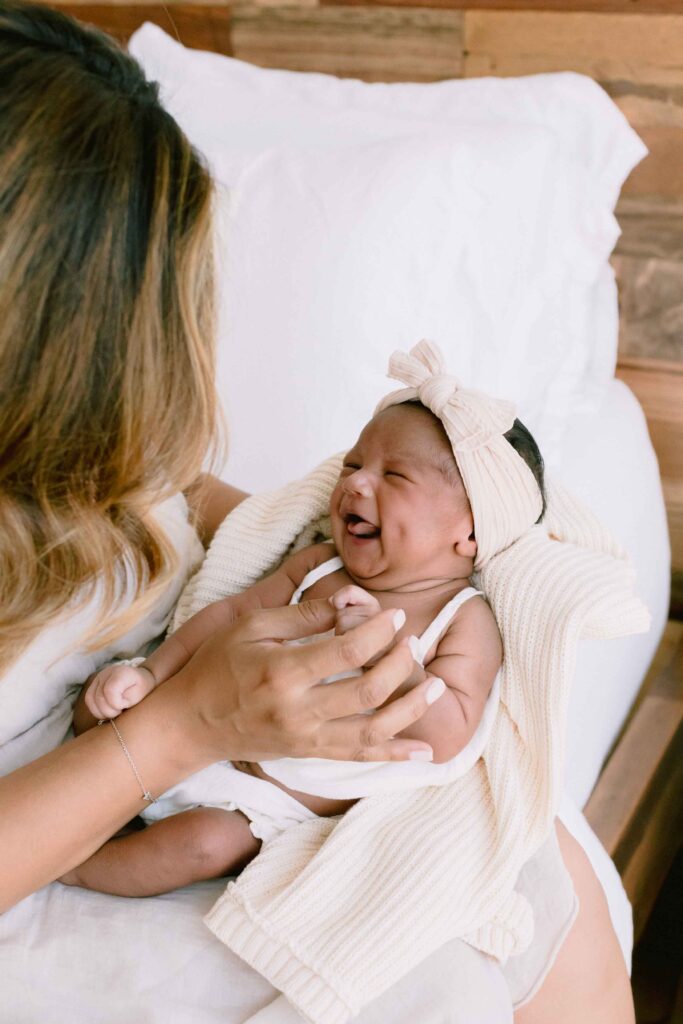 New mom holding her newborn baby who is giving a smile to mom