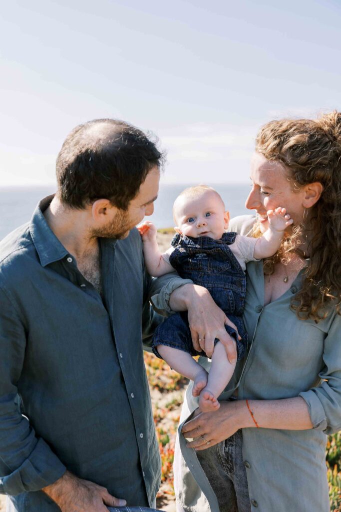 Parents looking lovingly at their baby boy at the beach