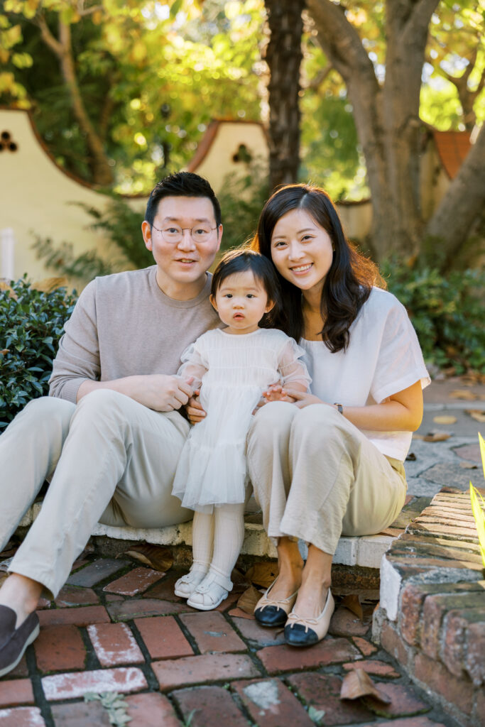 Family of 3 sitting on a brick step in the Allied Arts Guild in Menlo Park
