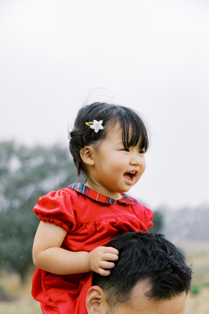 Little girl sitting on dad's shoulders and smiling