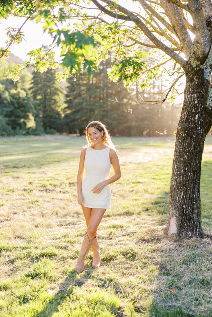 High school senior girl standing in an open meadow with the sun shining behind her at Foothills Preserve